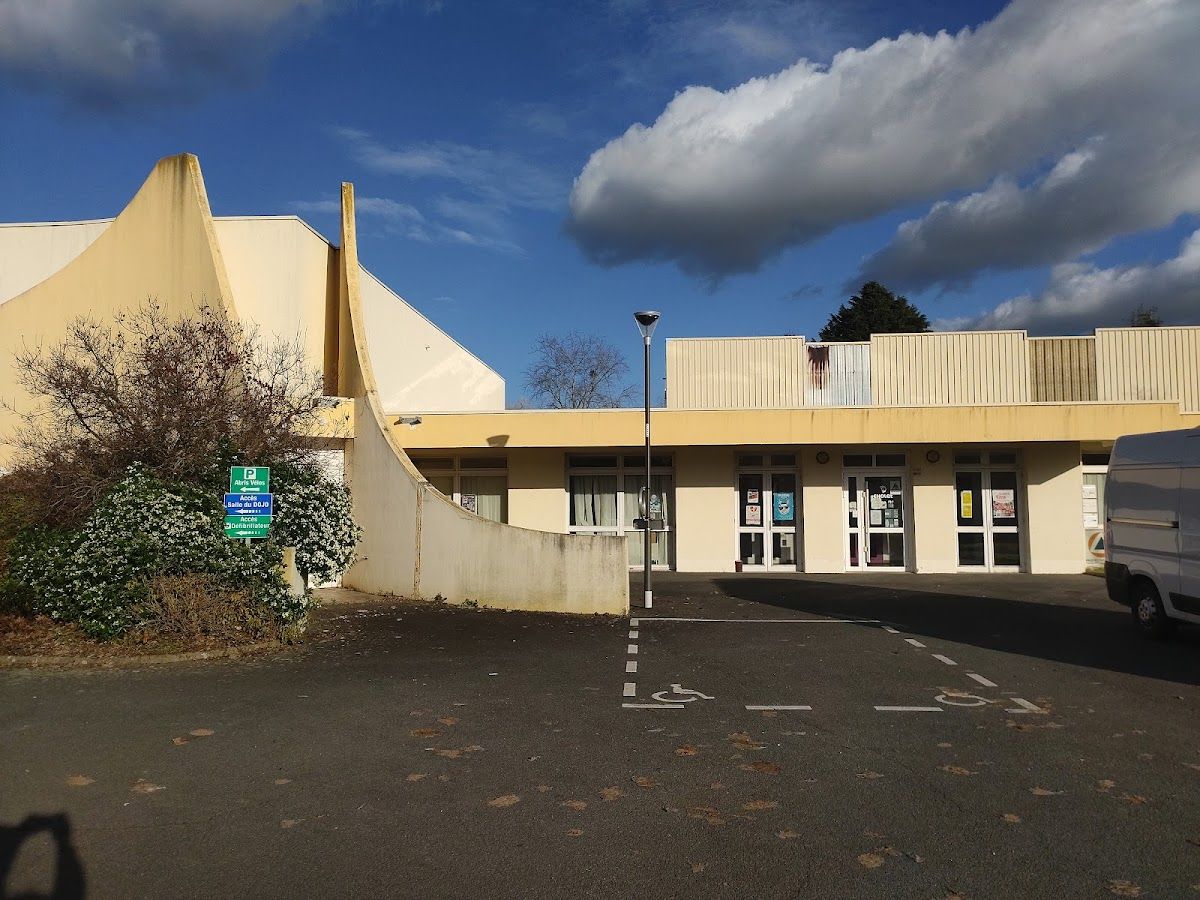 Façade du Dojo du Plessis avec son parking, et le panneau vert « Accès salle du dojo » à gauche